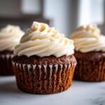 Close-up of moist gingerbread cupcakes topped with swirls of cream cheese frosting.
