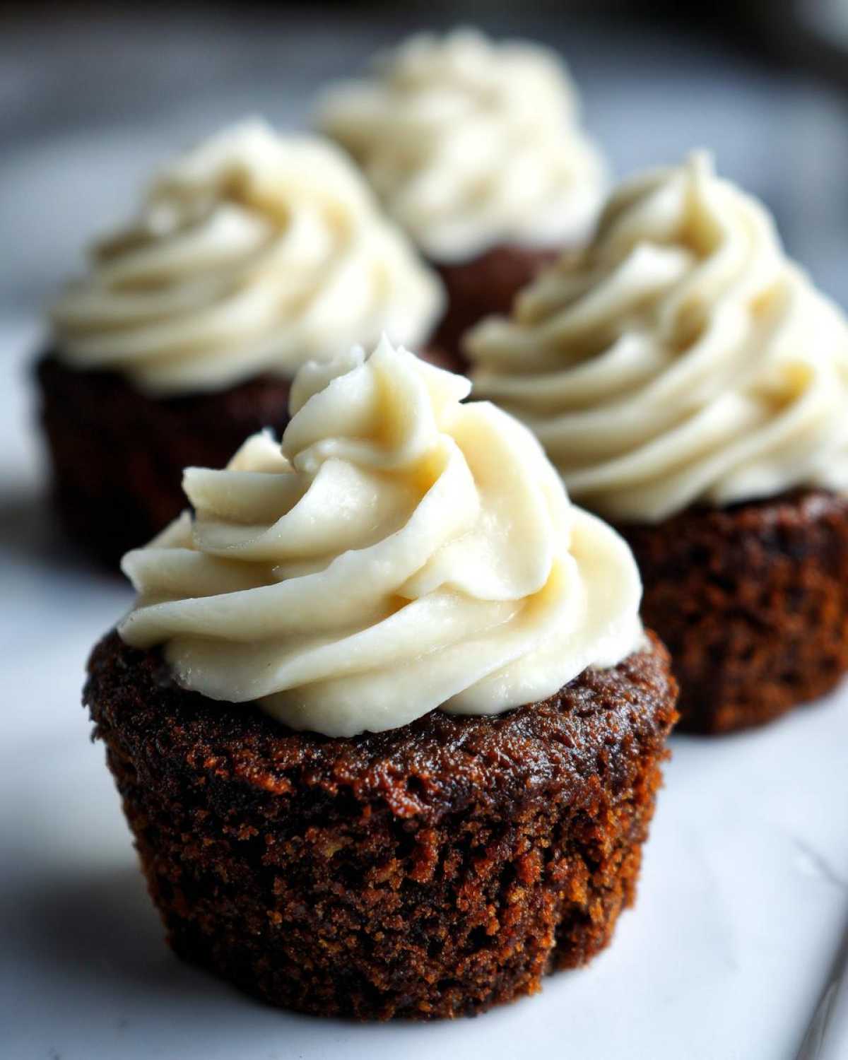 Close-up of a moist gingerbread cupcake topped with a swirl of white cream cheese frosting.