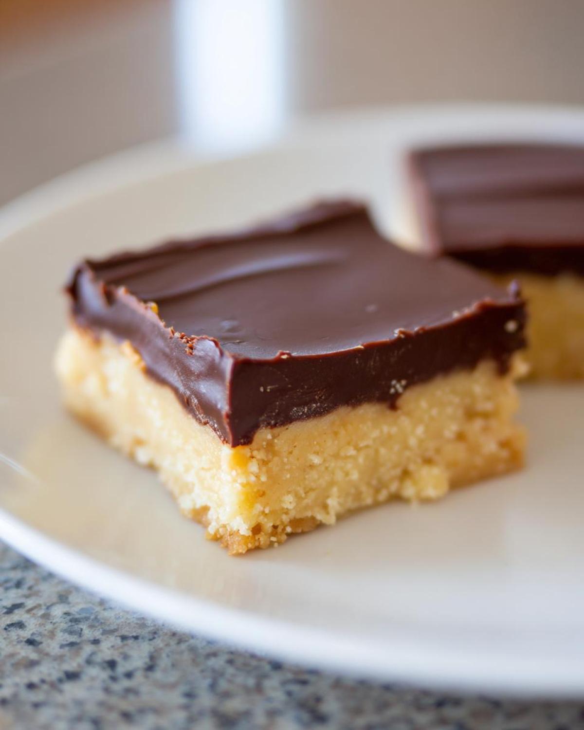 A single square of no-bake peanut butter bars topped with a thick layer of smooth chocolate ganache.