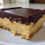 A single, thick square of no-bake peanut butter bars with a creamy peanut butter layer and a dark chocolate topping.