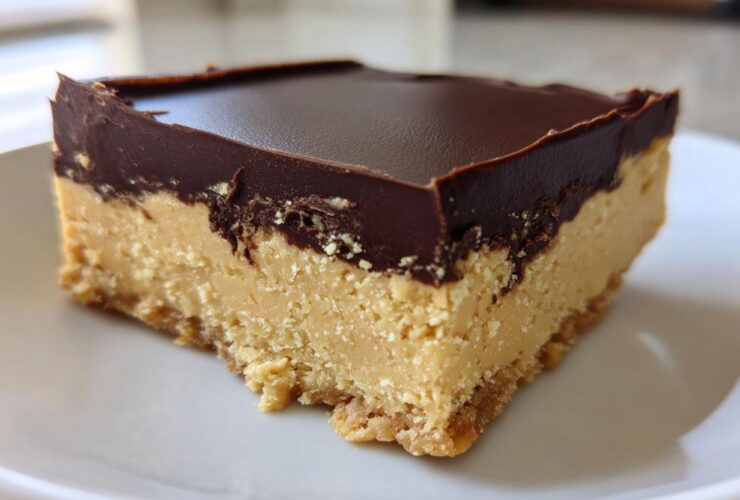 A single, thick square of no-bake peanut butter bars with a creamy peanut butter layer and a dark chocolate topping.