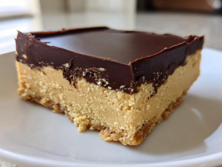A single, thick square of no-bake peanut butter bars with a creamy peanut butter layer and a dark chocolate topping.