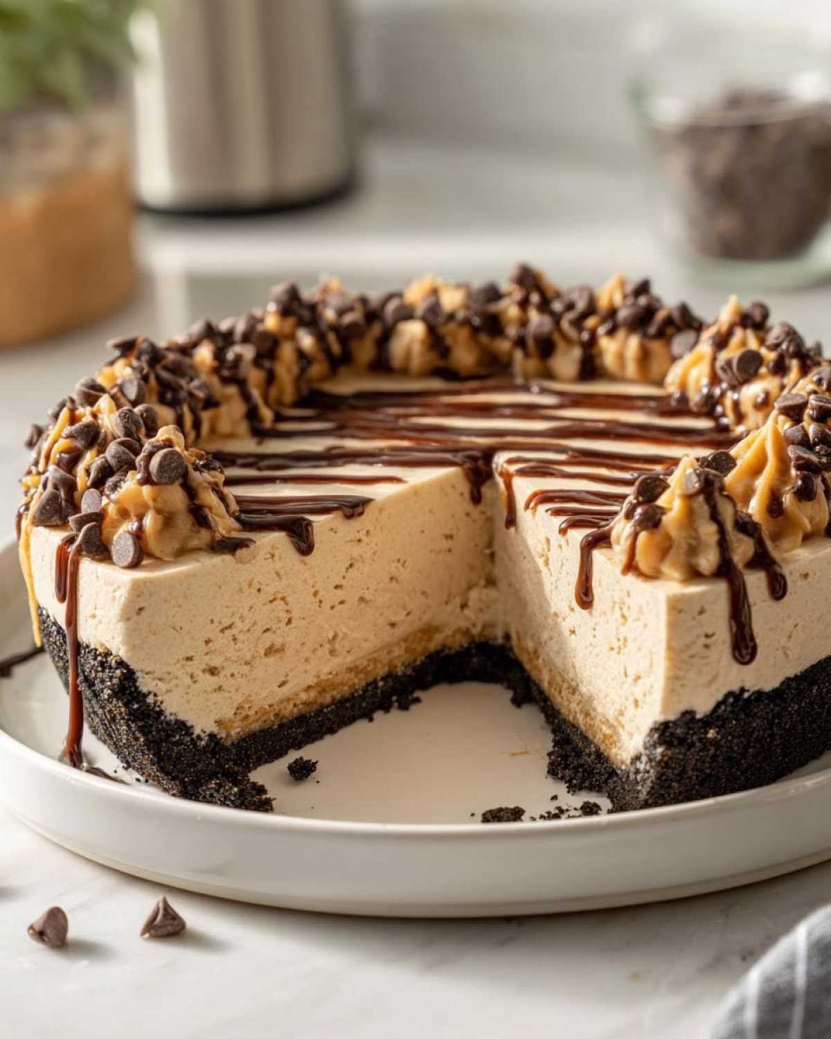 A slice removed from a decadent no-bake peanut butter pie topped with peanut butter swirls and chocolate chips.