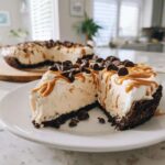 A decadent slice of no-bake peanut butter pie topped with caramel drizzle and chocolate chips.