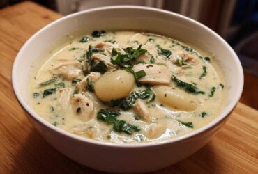 A close-up of a white bowl filled with creamy olive garden chicken gnocchi soup, featuring chicken, spinach, and potato gnocchi.