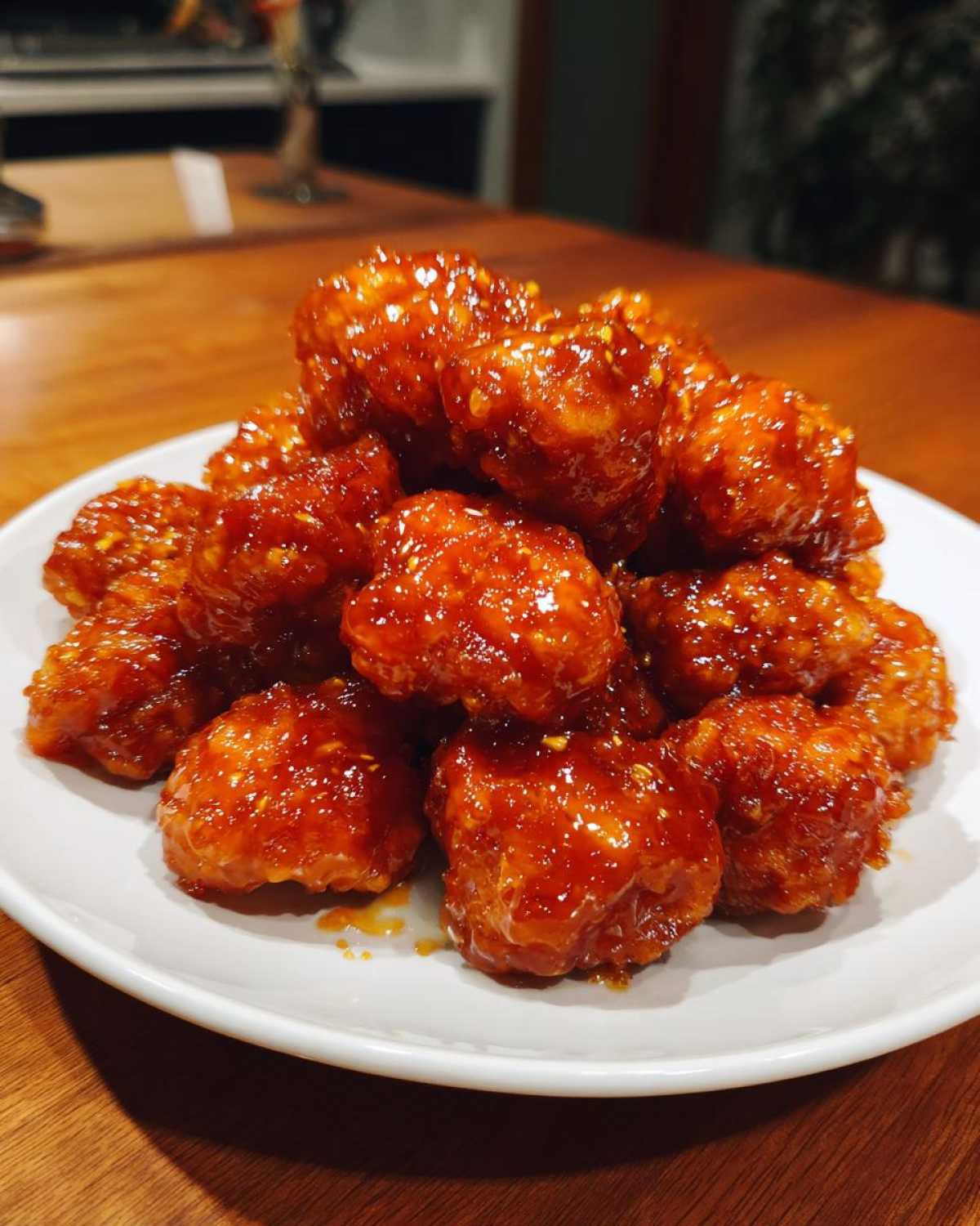 A mound of crispy, bite-sized pieces of orange chicken recipe coated in a thick, glossy, sweet and tangy orange sauce.
