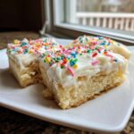 Three squares of thick, soft sugar cookie bars topped with white frosting and colorful sprinkles.