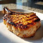 Close-up of a thick, juicy pork chop with beautiful grill marks, showing the effects of a great marinade for pork chops.