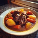 Close-up of tender chunks of beef, potatoes, and carrots in a rich broth of crockpot beef stew.