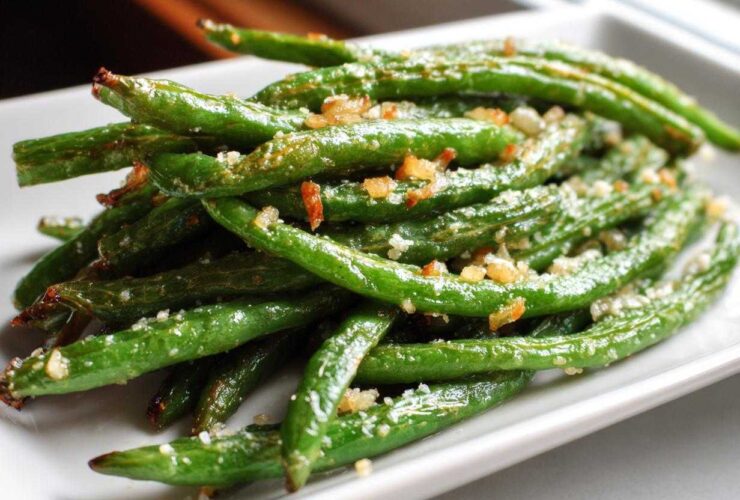 A close-up of bright green beans seasoned with garlic and salt, ready to eat.