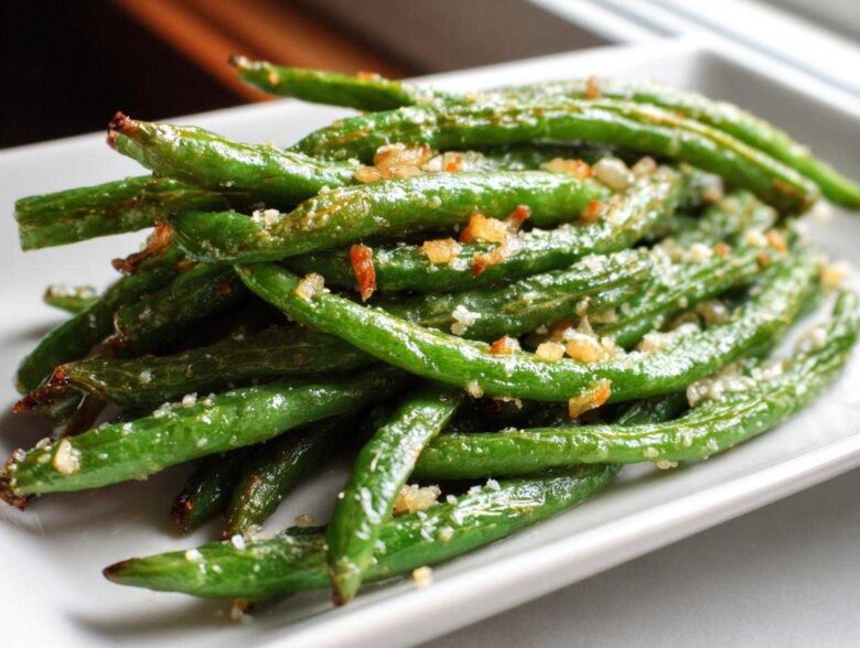 A close-up of bright green beans seasoned with garlic and salt, ready to eat.