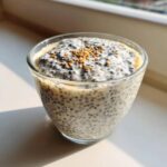 Close-up of creamy chia seed pudding in a glass, topped with toasted seeds.