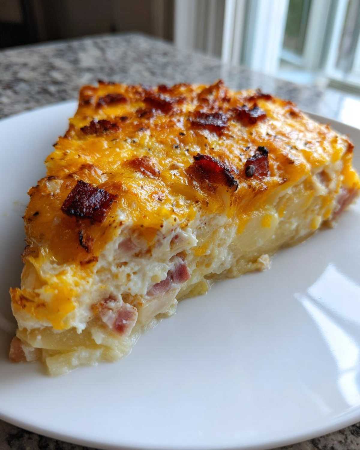 A thick, baked slice of scalloped potatoes and ham topped with melted cheddar and bacon bits.