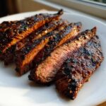 Close-up of medium-rare steak slices showing char marks and residue from the carne asada marinade.
