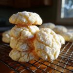 A stack of soft, powdered sugar-coated italian ricotta cookies resting on a black wire cooling rack.