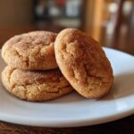 A stack of three soft, cinnamon-sugar coated pumpkin snickerdoodle cookies resting on a white plate.