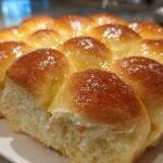 Close-up of freshly baked, soft sourdough discard rolls pulled apart, glistening with melted butter.