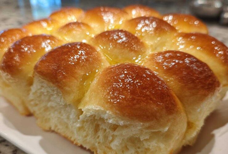 Close-up of freshly baked, soft sourdough discard rolls pulled apart, glistening with melted butter.