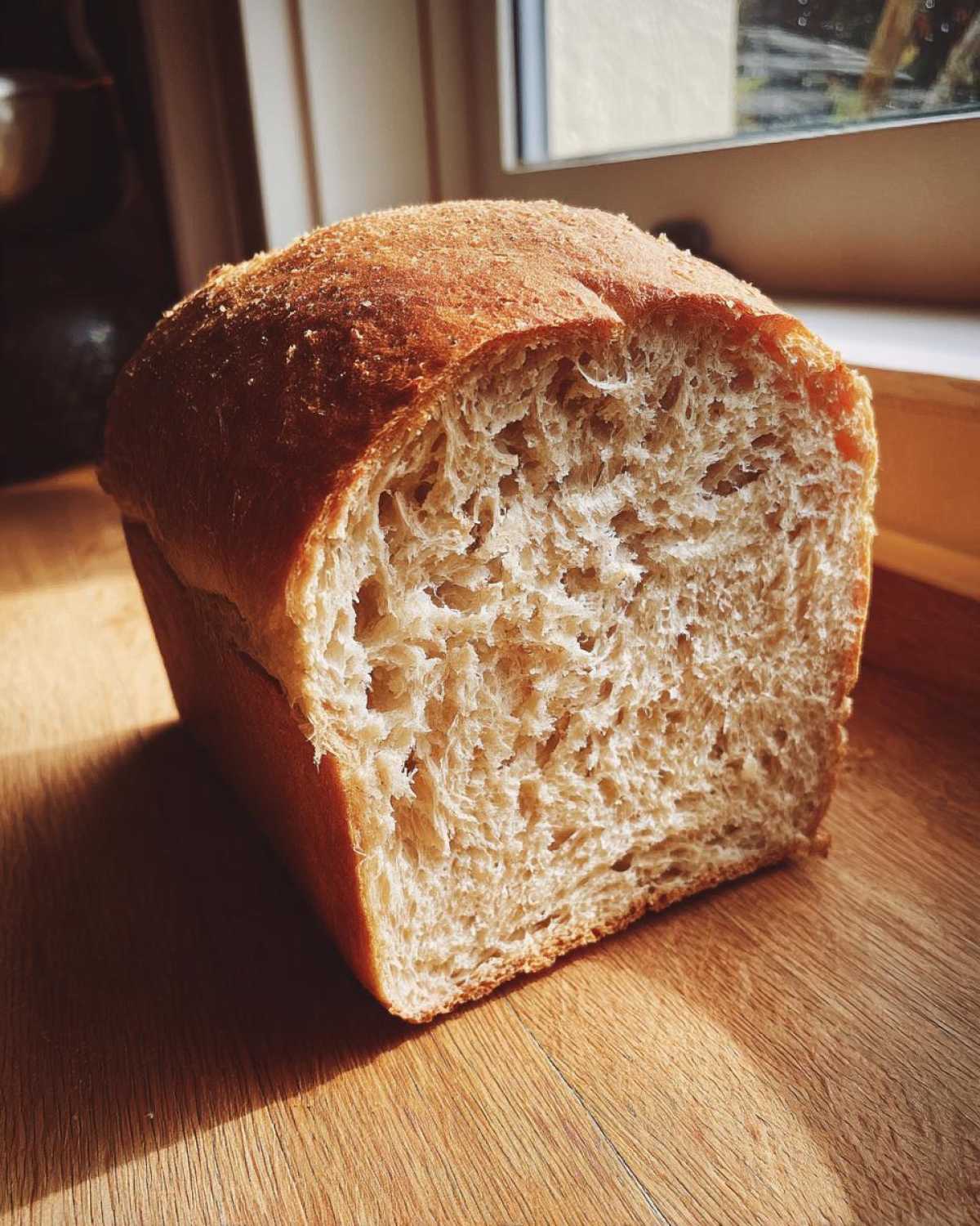 A freshly baked loaf of soft whole wheat bread, showing its fluffy interior texture.