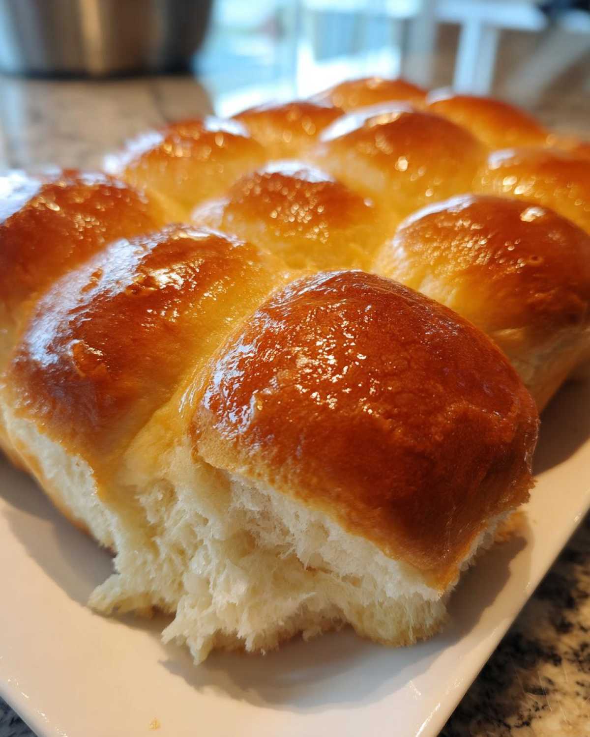 Close-up of soft, pull-apart sourdough discard rolls with a shiny, golden-brown glaze.