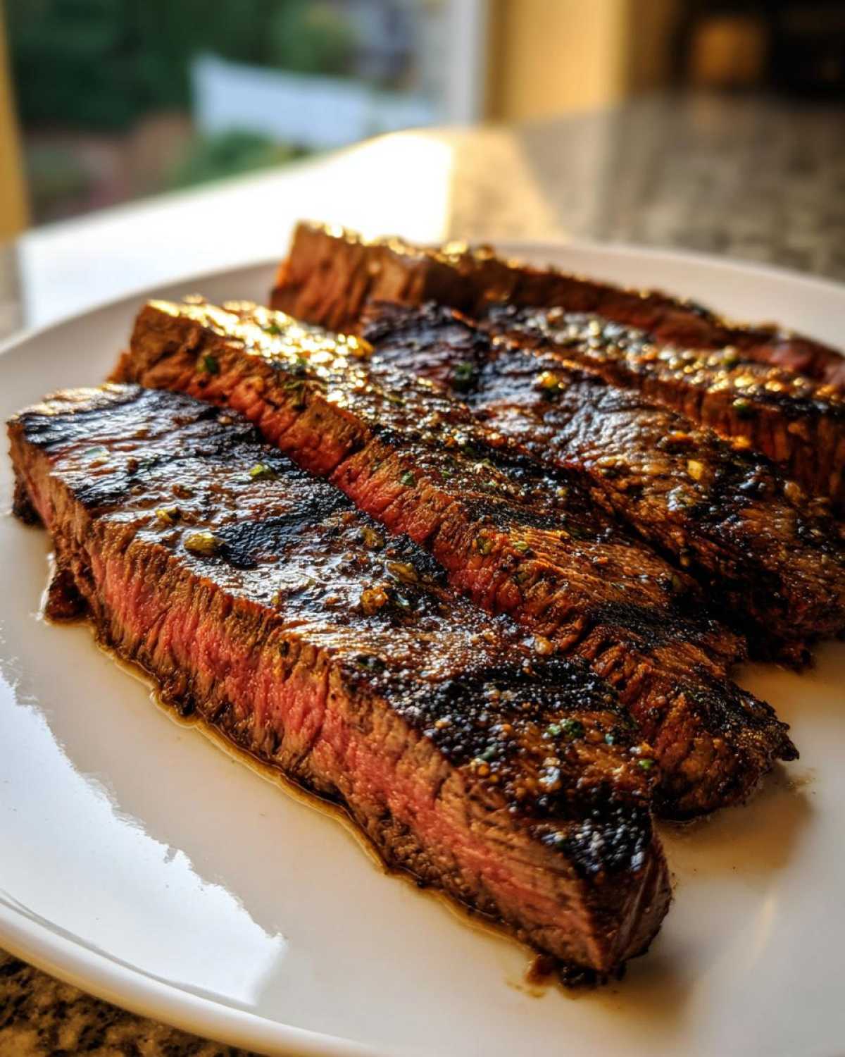 Slices of perfectly grilled steak showing a medium-rare center, coated in the flavorful carne asada marinade.