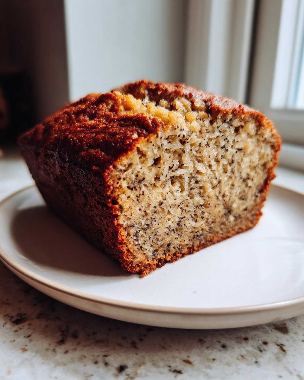 A close-up of a moist slice of sugar free banana bread showing the dark specks from the mashed banana.