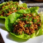 Three servings of flavorful chicken lettuce wraps topped generously with chopped green onions, ready to eat.