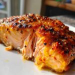 Close-up of a perfectly cooked, flaky salmon fillet with a sweet and spicy glaze, showcasing the moist interior.