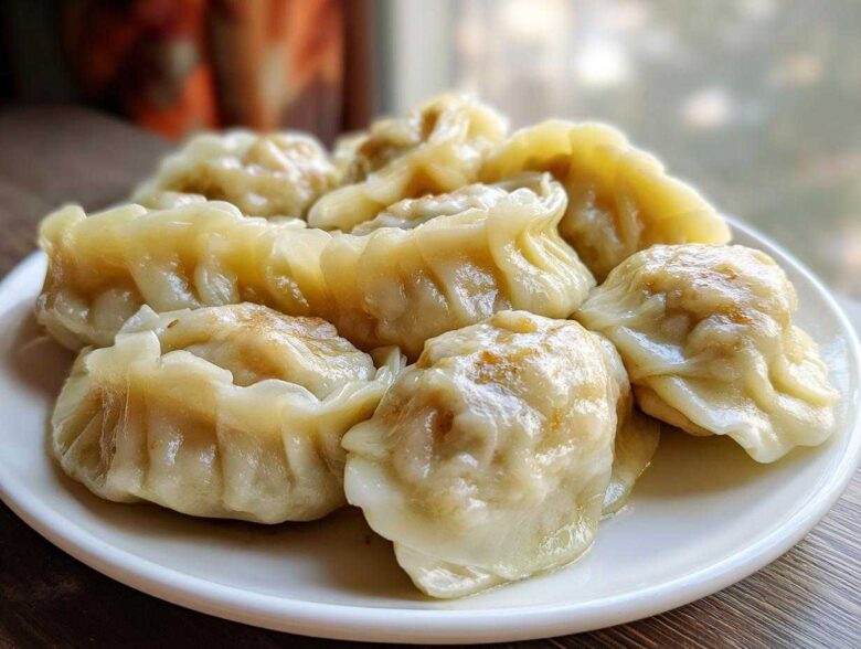 A close-up of several freshly steamed Traditional Chinese Dumplings arranged on a white plate.