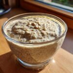 Close-up of thick chia seed pudding in a glass bowl, showing visible whole seeds.