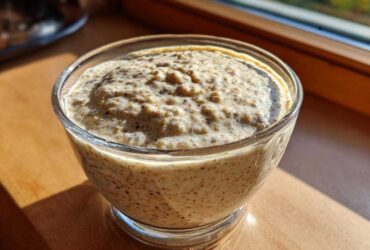 Close-up of thick chia seed pudding in a glass bowl, showing visible whole seeds.