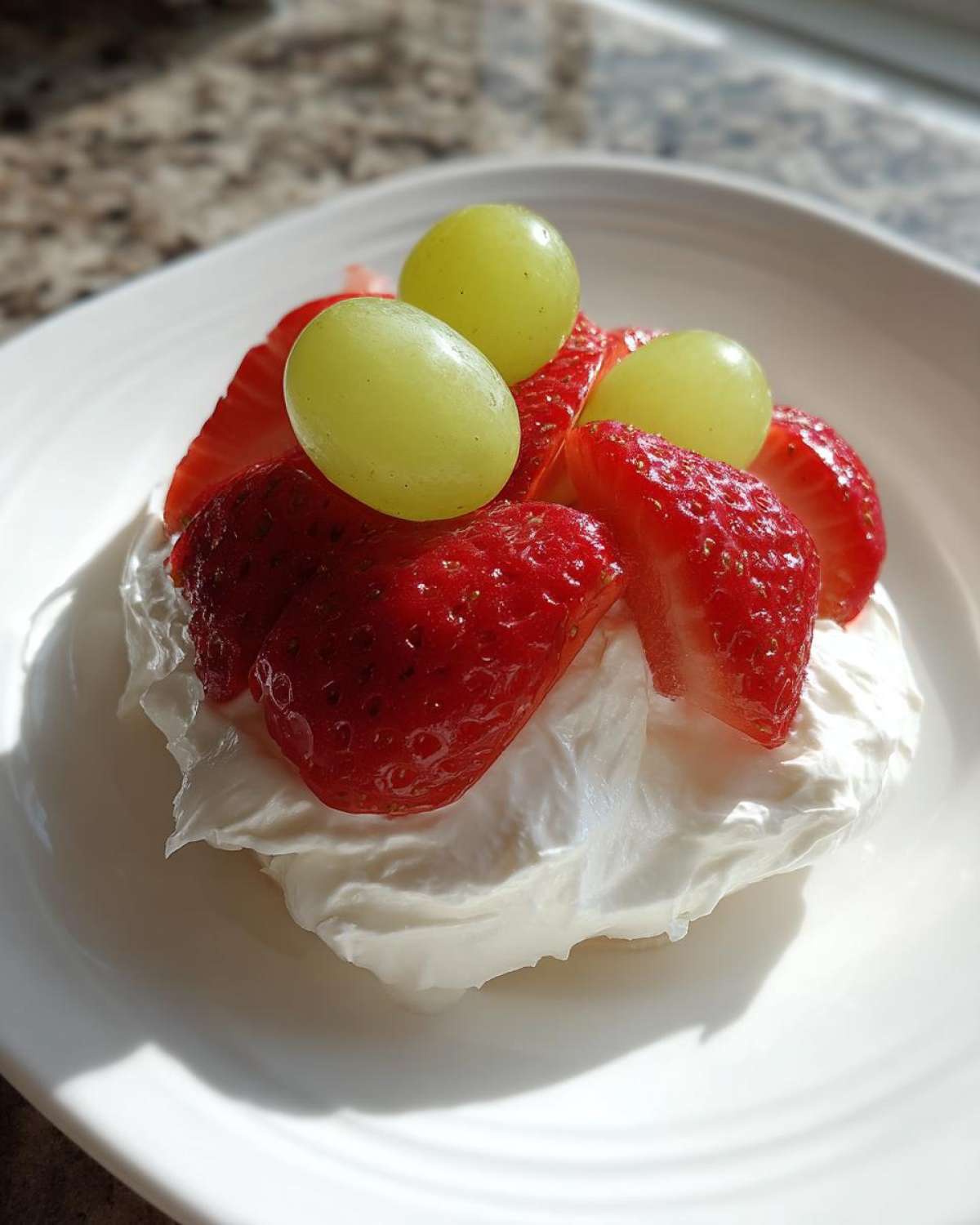 A dollop of cream cheese fruit dip topped with fresh strawberries and green grapes.