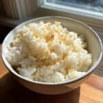 A close-up of fluffy white rice topped with golden brown garlic bits, representing delicious butter rice.