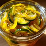 Close-up of thinly sliced cucumbers preserved in a bright yellow brine, making delicious bread and butter pickle.