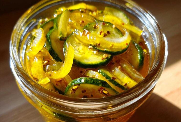 Close-up of thinly sliced cucumbers preserved in a bright yellow brine, making delicious bread and butter pickle.