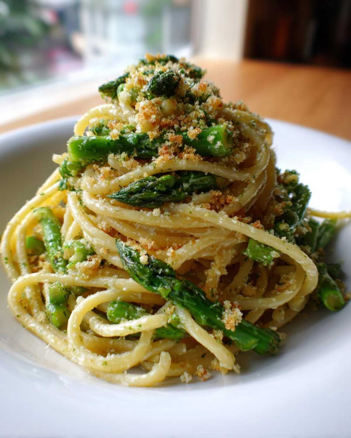 A beautifully plated serving of Asparagus Lemon Pasta with Parmesan Crumbs piled high on a white dish.