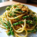A close-up of a serving of Asparagus Lemon Pasta with Parmesan Crumbs, featuring bright green asparagus spears mixed with pasta.