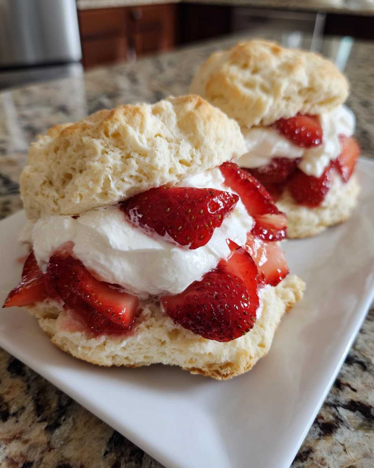 Two servings of fluffy Breakfast Strawberry Shortcakes with Quick Jam, filled with whipped cream and fresh strawberries.