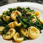 Close-up of orecchiette pasta tossed with vibrant green Broccoli Raab Pasta with Chili Flakes and seasonings.