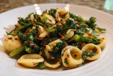 Close-up of Orecchiette pasta tossed with vibrant green Broccoli Raab Pasta with Chili Flakes.