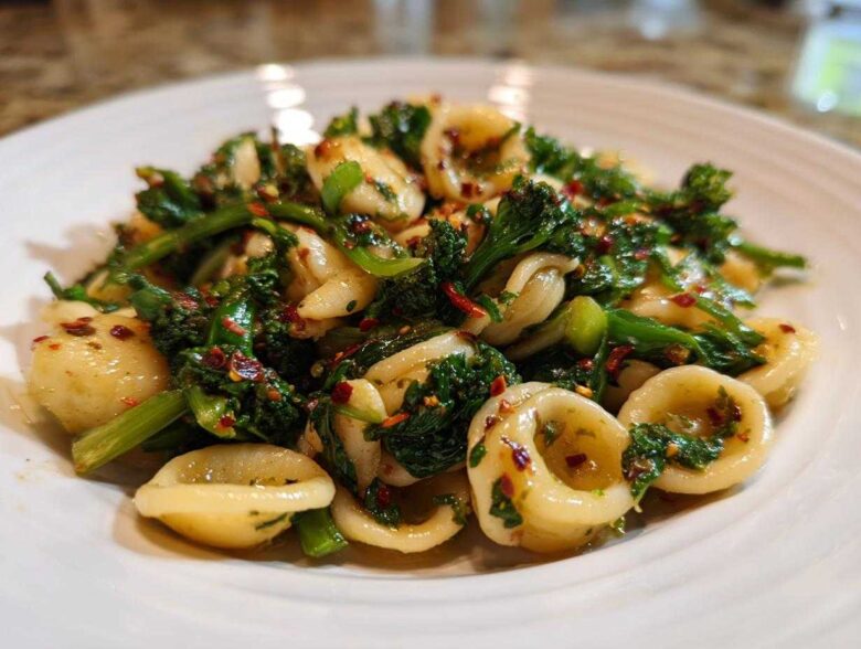 Close-up of Orecchiette pasta tossed with vibrant green Broccoli Raab Pasta with Chili Flakes.