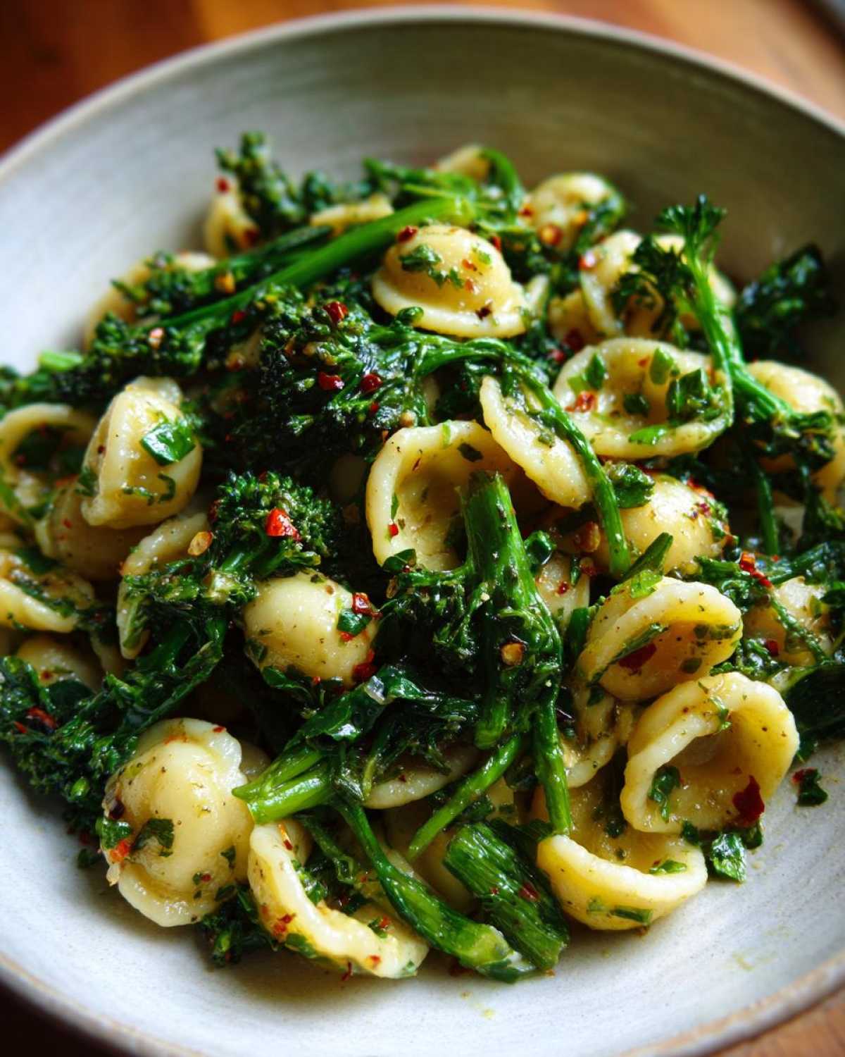 A close-up of orecchiette pasta tossed with vibrant green broccoli raab and red chili flakes, making Broccoli Raab Pasta with Chili Flakes.