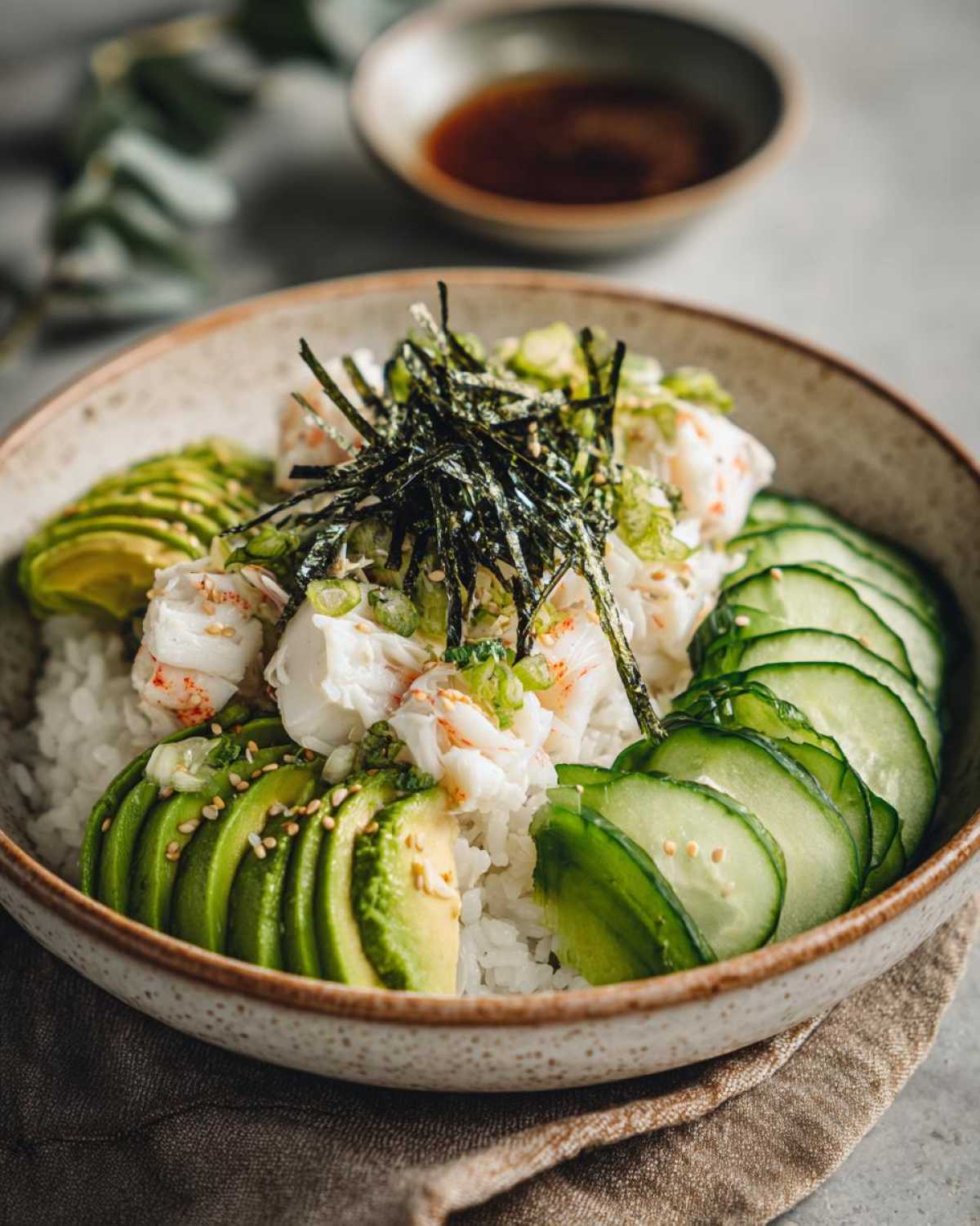 A beautiful California Sushi Bowl with Crab served over rice, topped with sliced avocado, cucumber, and shredded nori.