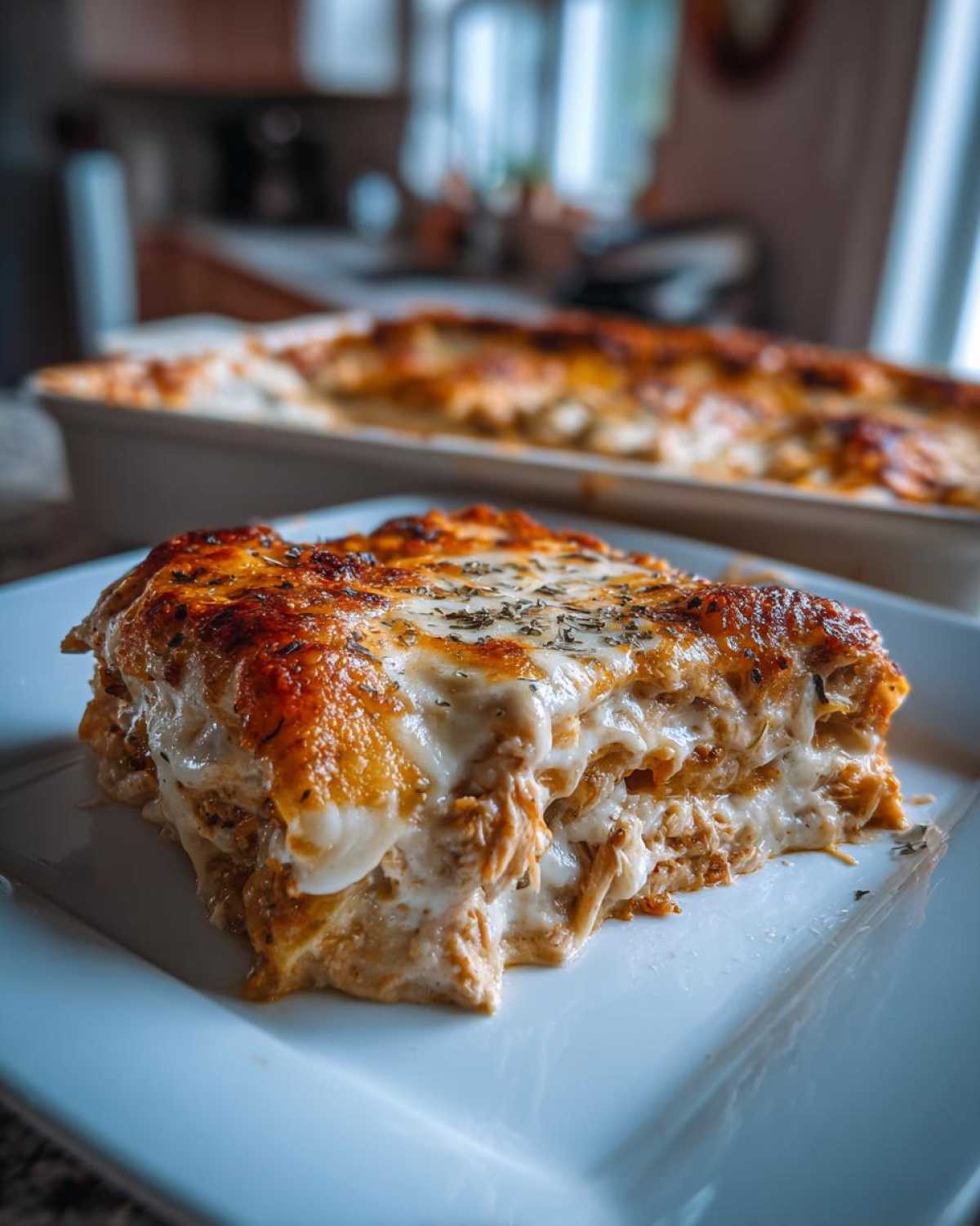 A close-up of a thick slice of Cheesy Chicken Enchilada Bake with melted, browned cheese topping.