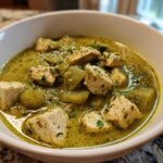 Close-up of a white bowl filled with rich, green Chile Verde Pork Stew with tomatillos and chunks of seasoned meat.