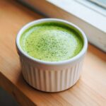 Close-up of bright green Cilantro Lime Crema, likely made with herbs, in a small white fluted ramekin.