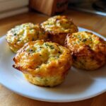 Four freshly baked Garden Herb Egg Muffins with golden brown tops and sprinkled herbs, served on a white plate.