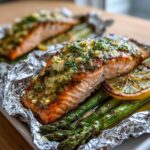 Close-up of a perfectly cooked Garlic Dijon Salmon Packet featuring salmon over asparagus with a charred lemon slice.