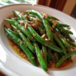 Vibrant green beans tossed in a rich brown butter sauce with slivered almonds, classic Green Bean Almondine.