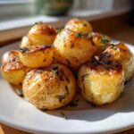 A close-up of perfectly golden Herb Roasted New Potatoes seasoned with fresh rosemary and thyme.